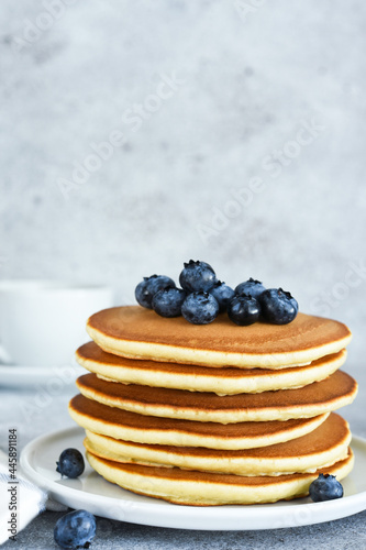 Homemade American pancakes with berries and maple syrup for breakfast on a concrete background.