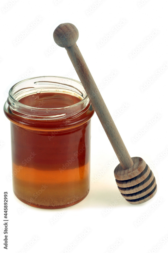 Pot de miel liquide et cuillère à miel en gros plan sur fond blanc Pot de miel liquide et cuillère à miel en gros plan sur fond blanc