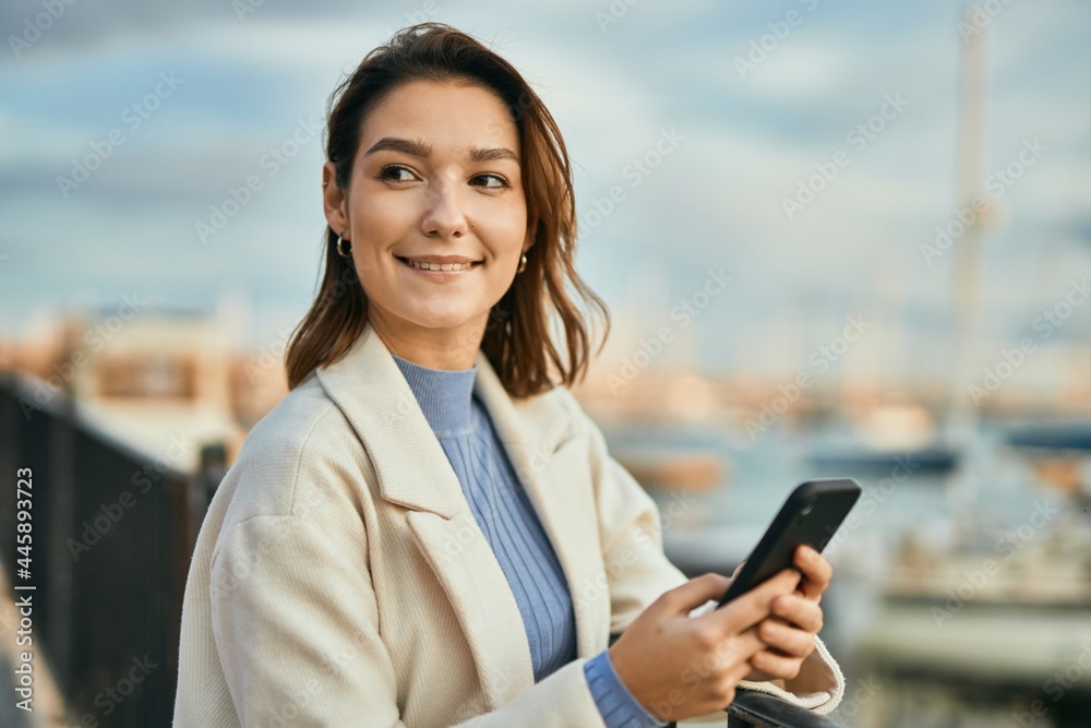 Young hispanic woman smiling happy using smartphone at the city. Young hispanic woman smiling happy using smartphone at the city.