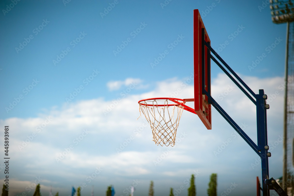 Basketball hoop with a red backboard on a blue sky background.