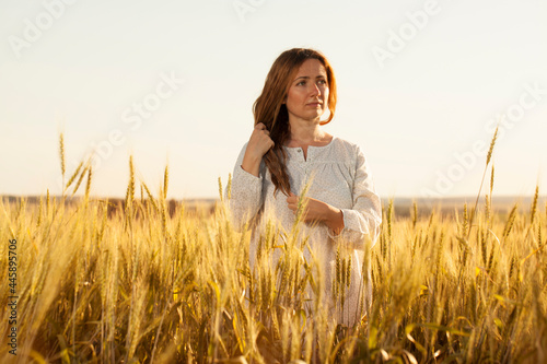 Young woman stands in the middle of a wheat field