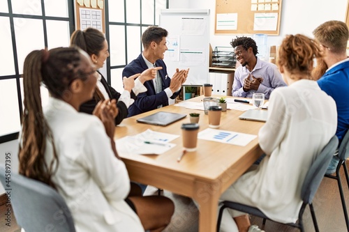 Group of business workers smiling and clapping to partner at the office.