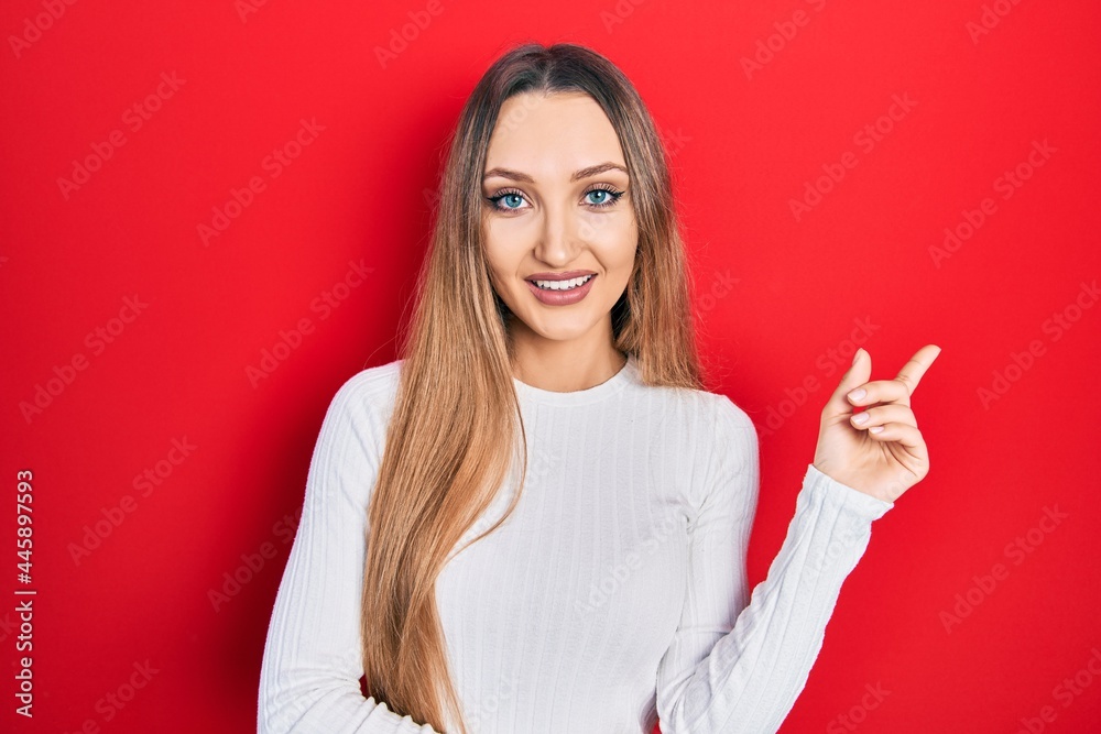 Young blonde girl wearing casual clothes smiling happy pointing with hand and finger to the side Young blonde girl wearing casual clothes smiling happy pointing with hand and finger to the side