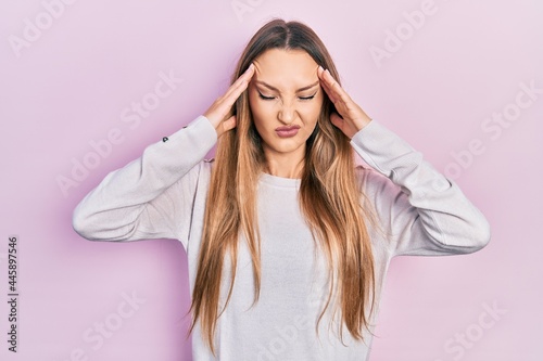 Young blonde girl wearing casual clothes with hand on head, headache because stress. suffering migraine.