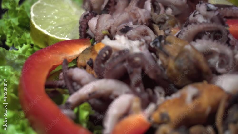  Sea cocktail, sea food, small octopus and mussels with sweet pepper on salad leaves macro shot