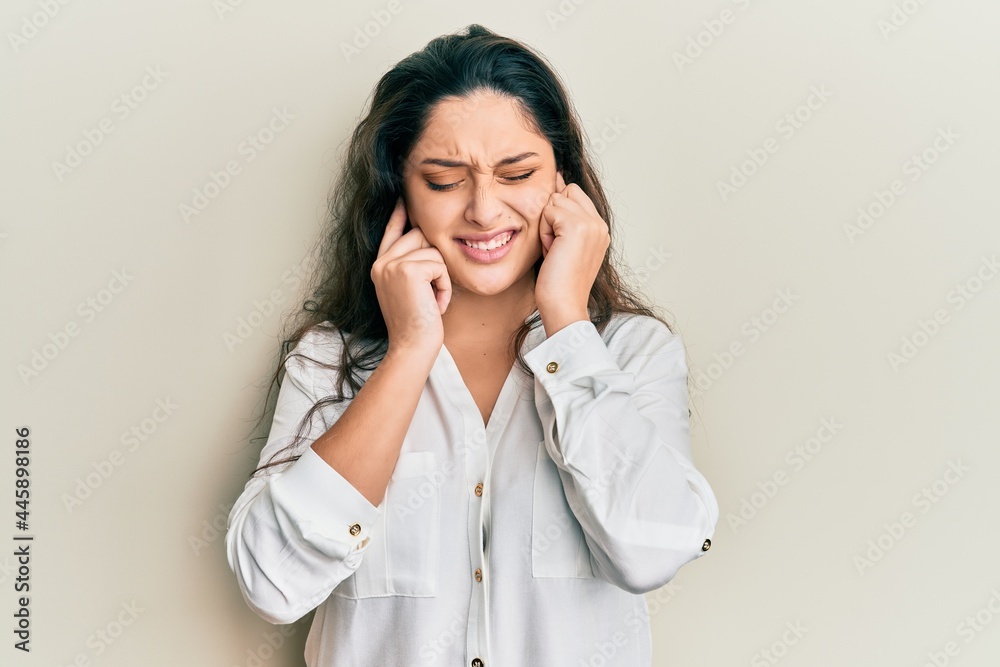 Beautiful middle eastern woman wearing casual clothes covering ears with fingers with annoyed expression for the noise of loud music. deaf concept. Beautiful middle eastern woman wearing casual clothes covering ears with fingers with annoyed expression for the noise of loud music. deaf concept.