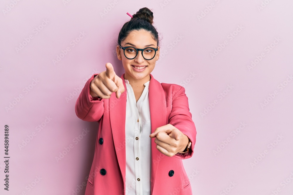 Beautiful middle eastern woman wearing business jacket and glasses pointing to you and the camera with fingers, smiling positive and cheerful