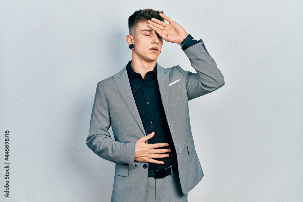 Young caucasian boy with ears dilation wearing business jacket touching forehead for illness and fever, flu and cold, virus sick Young caucasian boy with ears dilation wearing business jacket touching forehead for illness and fever, flu and cold, virus sick