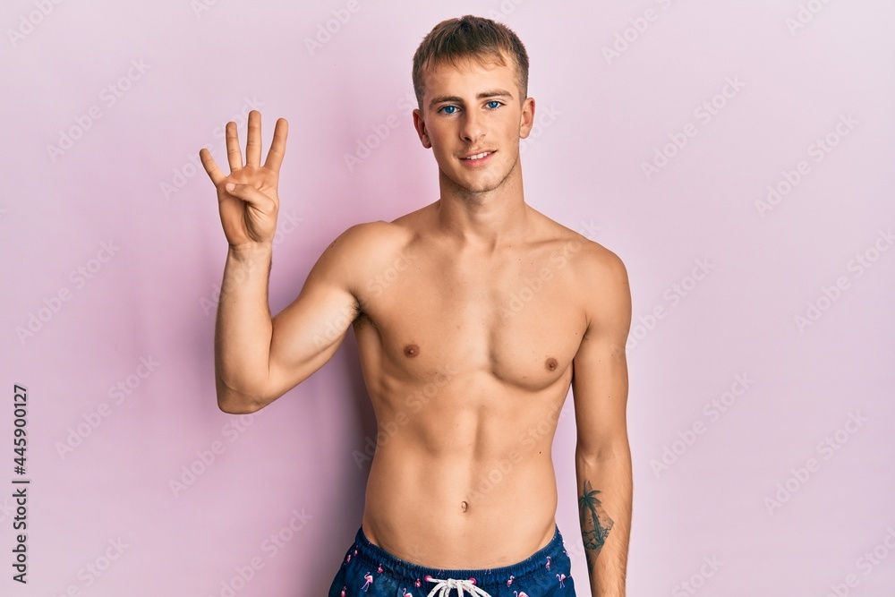 Young caucasian man wearing swimwear showing and pointing up with fingers number four while smiling confident and happy. Young caucasian man wearing swimwear showing and pointing up with fingers number four while smiling confident and happy.