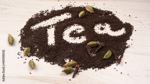 Black Tea Powder or dry dust tea powder, chai patti isolated in wooden bowl with Cardamom, Clove and Ginger.