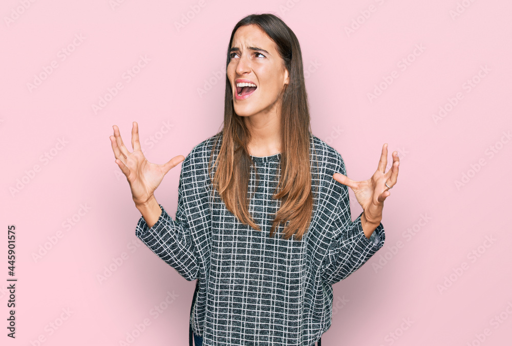 Young beautiful woman wearing casual clothes crazy and mad shouting and yelling with aggressive expression and arms raised. frustration concept. Young beautiful woman wearing casual clothes crazy and mad shouting and yelling with aggressive expression and arms raised. frustration concept.