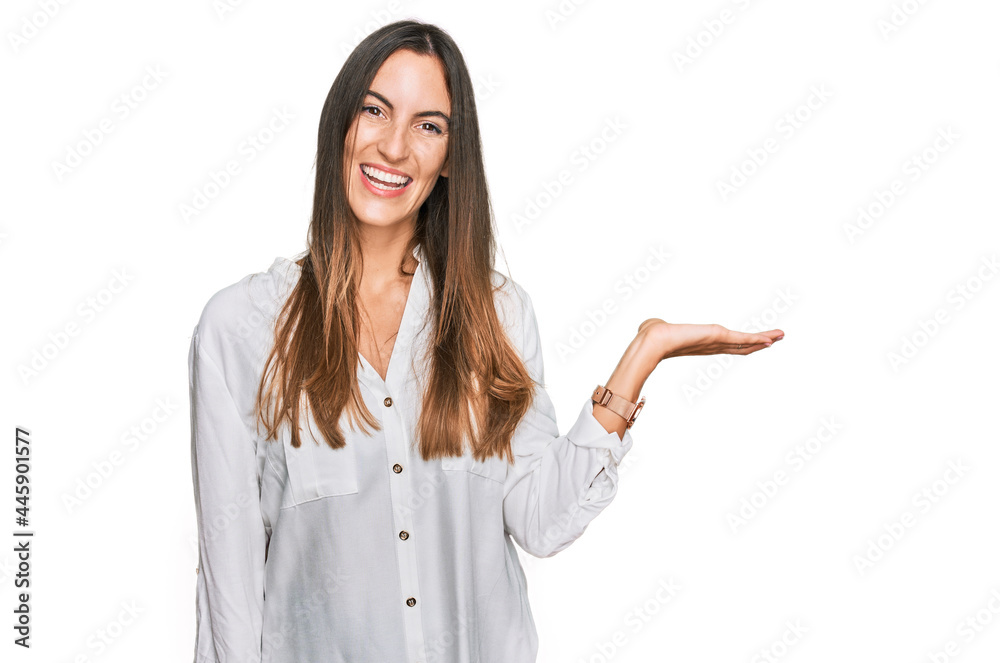 Young beautiful woman wearing casual clothes smiling cheerful presenting and pointing with palm of hand looking at the camera. Young beautiful woman wearing casual clothes smiling cheerful presenting and pointing with palm of hand looking at the camera.