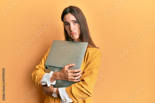 Young beautiful woman holding laptop depressed and worry for distress, crying angry and afraid. sad expression.