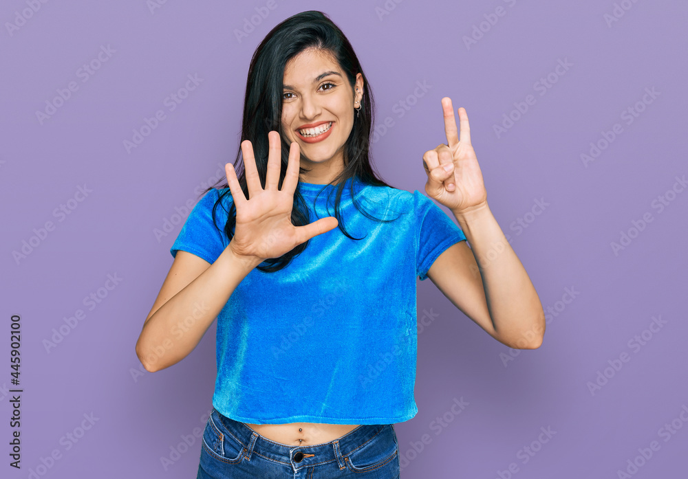 Young hispanic woman wearing casual clothes showing and pointing up with fingers number seven while smiling confident and happy. Young hispanic woman wearing casual clothes showing and pointing up with fingers number seven while smiling confident and happy.