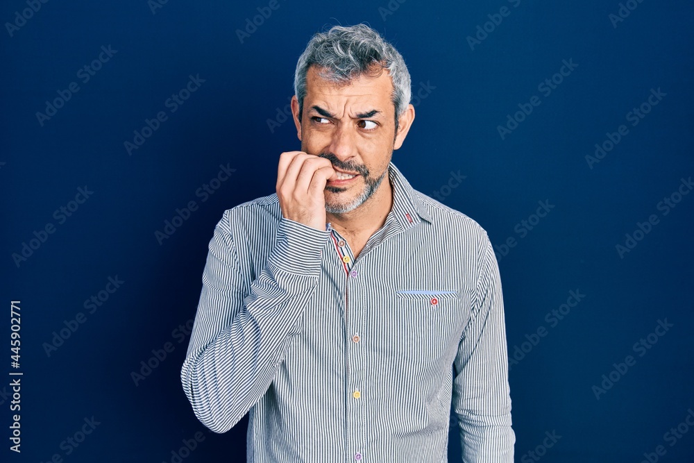 Handsome middle age man with grey hair wearing business shirt looking stressed and nervous with hands on mouth biting nails. anxiety problem. Handsome middle age man with grey hair wearing business shirt looking stressed and nervous with hands on mouth biting nails. anxiety problem.