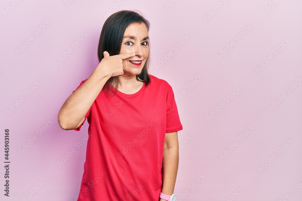 Middle age hispanic woman wearing casual clothes pointing with hand finger to face and nose, smiling cheerful. beauty concept Middle age hispanic woman wearing casual clothes pointing with hand finger to face and nose, smiling cheerful. beauty concept