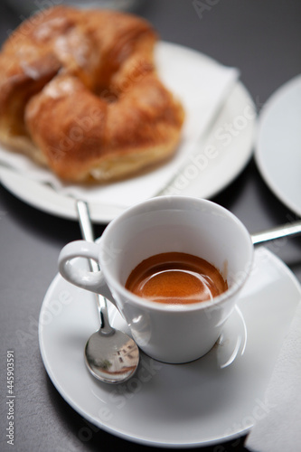 Traditional Italian breakfast. Fresh croissants with cream and sugar powder  espresso coffee and cappuccino on a black wooden table in Milan  Lombardy  Italy. European food and pastry.