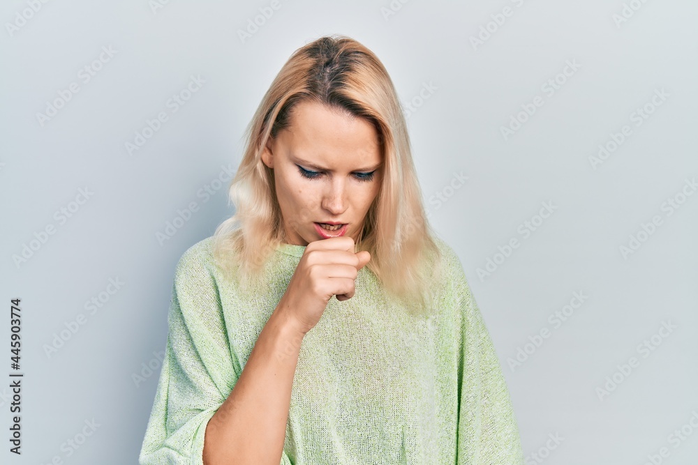 Beautiful caucasian blonde woman wearing casual winter sweater feeling unwell and coughing as symptom for cold or bronchitis. health care concept. Beautiful caucasian blonde woman wearing casual winter sweater feeling unwell and coughing as symptom for cold or bronchitis. health care concept.