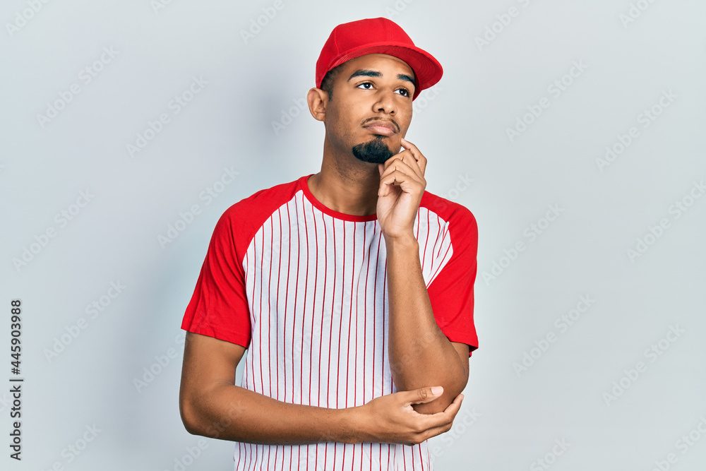 Young african american man wearing baseball uniform amazed and smiling to the camera while presenting with hand and pointing with finger. Young african american man wearing baseball uniform amazed and smiling to the camera while presenting with hand and pointing with finger.
