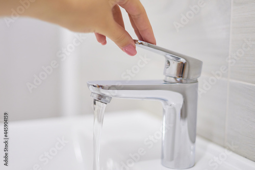 Fototapeta Naklejka Na Ścianę i Meble -   female hand opens a tap with water
