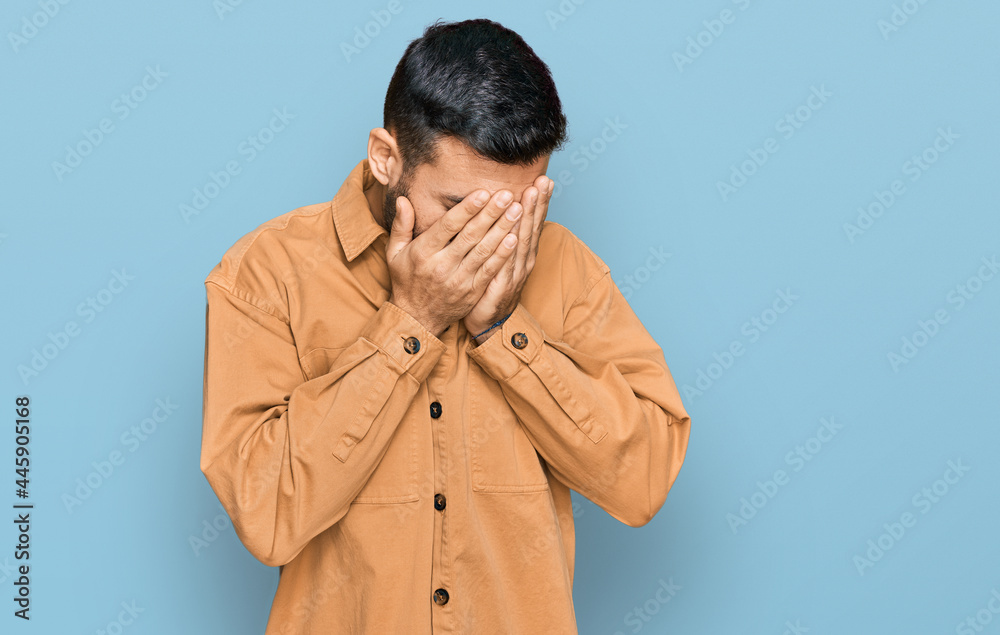 Young hispanic man wearing casual clothes with sad expression covering face with hands while crying. depression concept. Young hispanic man wearing casual clothes with sad expression covering face with hands while crying. depression concept.