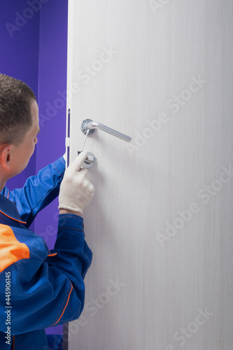 worker in uniform, fixing the door lock, there is a place for the inscription