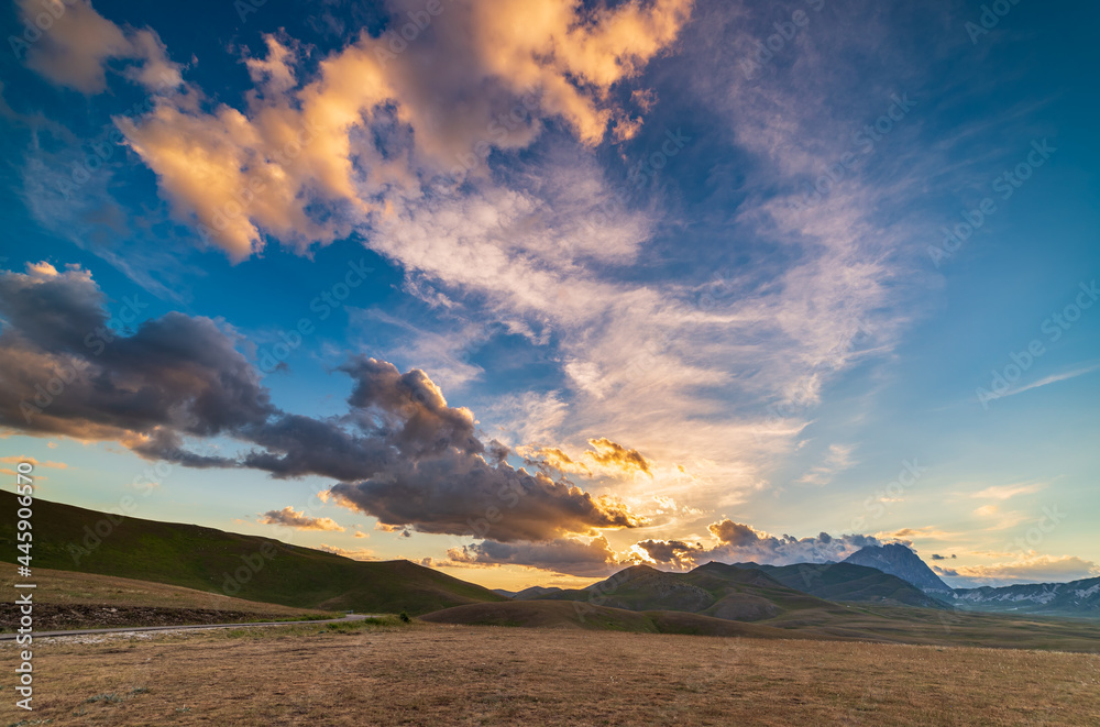 Sunset view point on rocky mountains, highlands and pastures. Campo Imperatore, Gran Sasso, Apennines, Italy. Colorful clouds in the sky on dramatic mountain ridge.