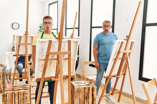 Group of middle age people artist at art studio scared and amazed with open mouth for surprise, disbelief face