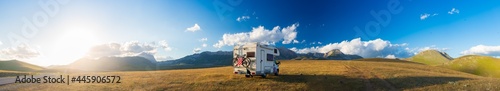 Sunset dramatic sky over camper van in Campo Imperatore highlands, Abruzzo, Italy. Epic clouds above unique highlands and rocky mountains landscape, alternative vanlife vacation concept.