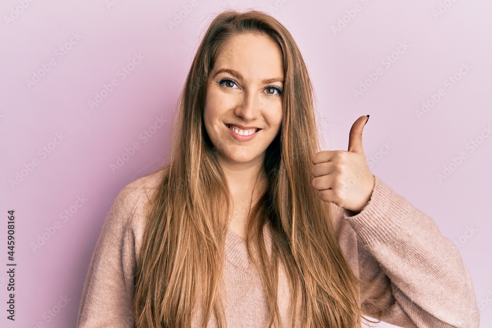 Young blonde woman wearing casual sweater smiling happy and positive, thumb up doing excellent and approval sign Young blonde woman wearing casual sweater smiling happy and positive, thumb up doing excellent and approval sign