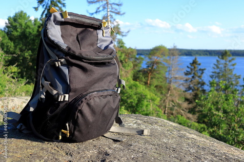 Dark grey backpack at a cliff with a view. Selective focus  the bag is isolated. Blurry nature in the background. Concept of outdoor living. Close up and isolated.  Stockholm  Sweden  Europe. 