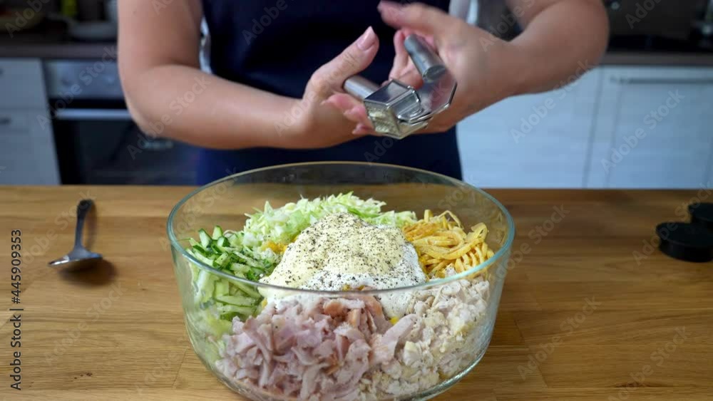 Woman squeezes garlic into a bowl of fresh vegetables and chicken salad. Preparing food in the home kitchen. Close up Woman squeezes garlic into a bowl of fresh vegetables and chicken salad. Preparing food in the home kitchen. Close up