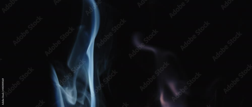 Colorful incense smoke swirling on black background in slow motion. Colorful incense smoke swirling on black background in slow motion.