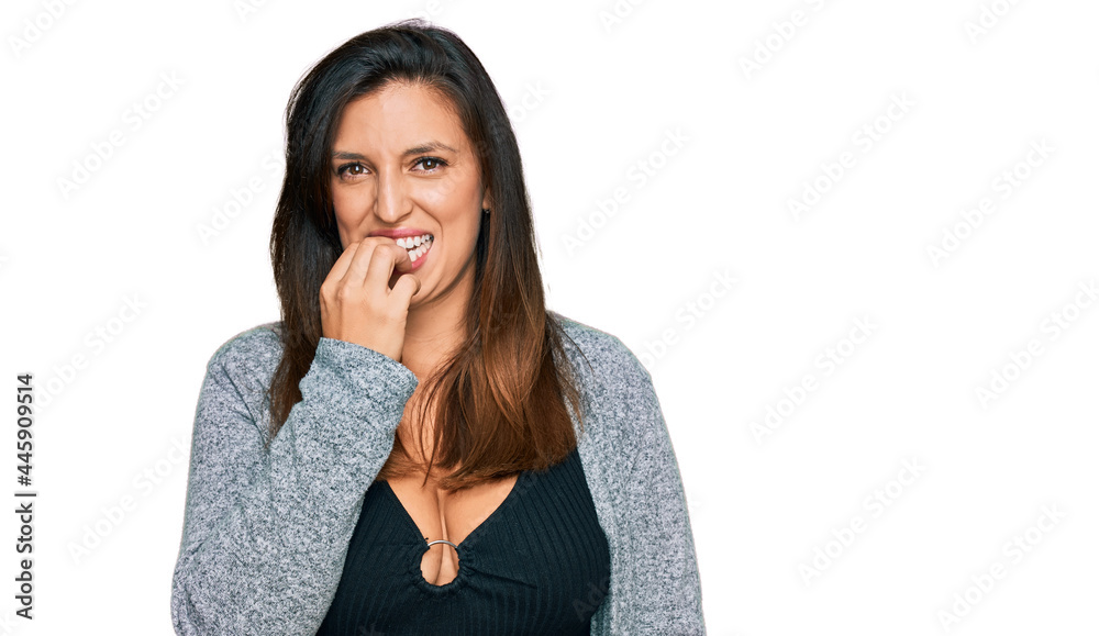 Beautiful hispanic woman wearing casual clothes looking stressed and nervous with hands on mouth biting nails. anxiety problem. Beautiful hispanic woman wearing casual clothes looking stressed and nervous with hands on mouth biting nails. anxiety problem.