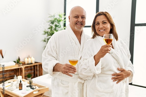 Middle age hispanic couple smiling happy toasting whit champagne at beauty center.