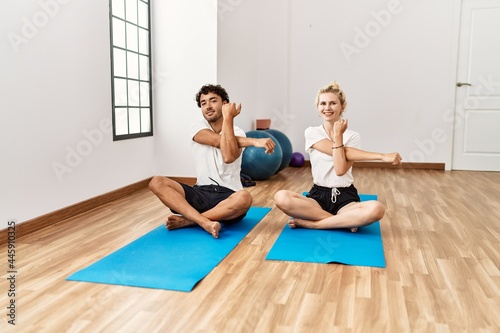 Young sporty couple smiling happy stretching at sport center.
