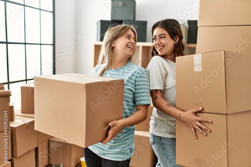 Young beautiful couple smiling happy holding cardboard boxes at new home.