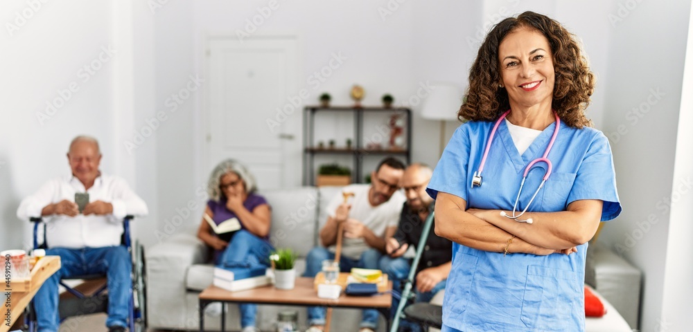 Middle age doctor woman smiling happy standing with arms crossed gesture at nursing home.