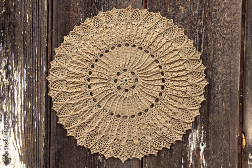 Beautiful closeup crochet doily on old wooden background photo