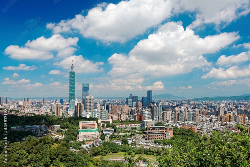 Fototapeta premium Aerial panorama of Downtown Taipei, vibrant capital city of Taiwan, with prominent Taipei 101 Tower among skyscrapers in Xinyi District & Yangmingshan Mountain on distant horizon under blue sunny sky