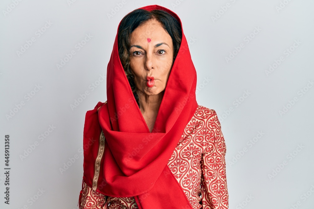 Middle age hispanic woman wearing tradition sherwani saree clothes making fish face with lips, crazy and comical gesture. funny expression. Middle age hispanic woman wearing tradition sherwani saree clothes making fish face with lips, crazy and comical gesture. funny expression.