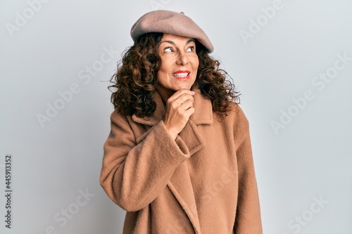 Middle age hispanic woman wearing french look with beret with hand on chin thinking about question, pensive expression. smiling with thoughtful face. doubt concept.