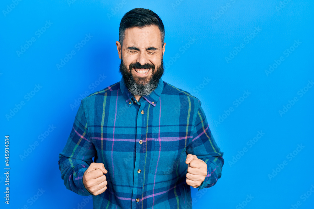 Young hispanic man wearing casual clothes excited for success with arms raised and eyes closed celebrating victory smiling. winner concept. Young hispanic man wearing casual clothes excited for success with arms raised and eyes closed celebrating victory smiling. winner concept.