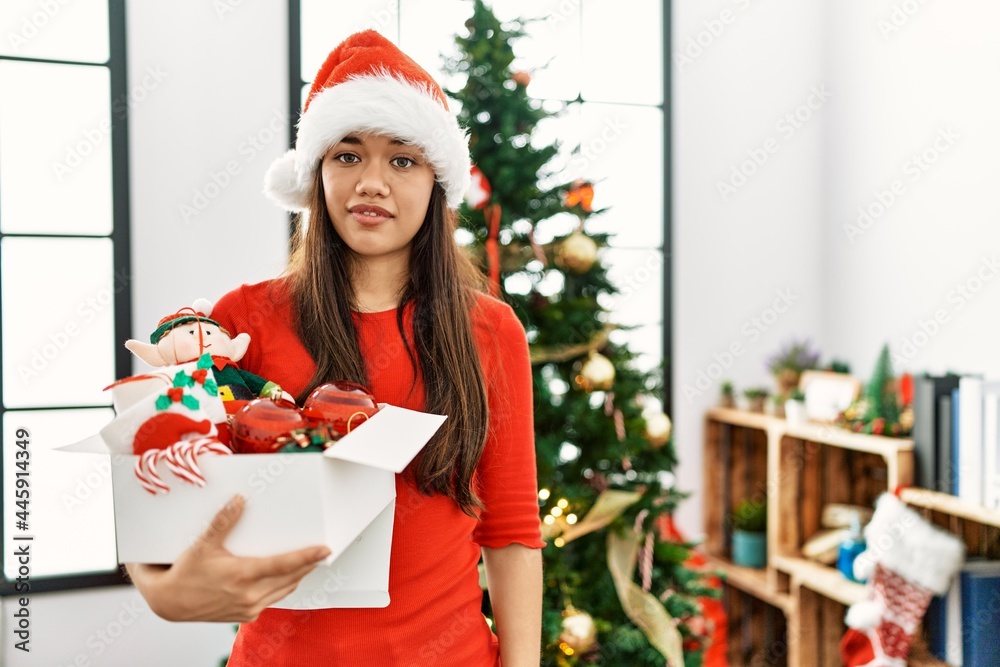 Young brunette woman standing by christmas tree holding decoration looking sleepy and tired, exhausted for fatigue and hangover, lazy eyes in the morning. Young brunette woman standing by christmas tree holding decoration looking sleepy and tired, exhausted for fatigue and hangover, lazy eyes in the morning.