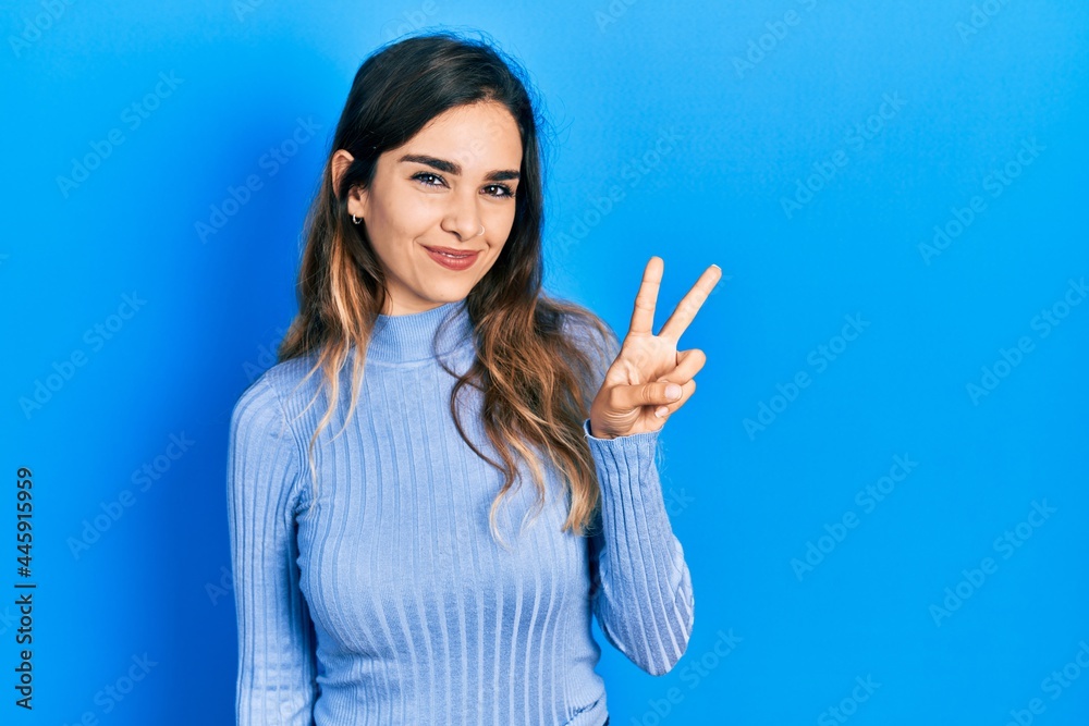 Young hispanic girl wearing casual clothes showing and pointing up with fingers number two while smiling confident and happy. Young hispanic girl wearing casual clothes showing and pointing up with fingers number two while smiling confident and happy.