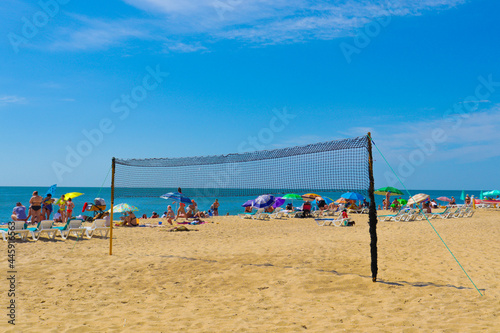 Beach volleyball.  The beach net is stretched on the beach by the sea.  Sea sand and volleyball