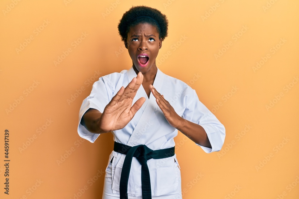 Young african american girl wearing karate kimono and black belt angry and mad screaming frustrated and furious, shouting with anger looking up. Young african american girl wearing karate kimono and black belt angry and mad screaming frustrated and furious, shouting with anger looking up.