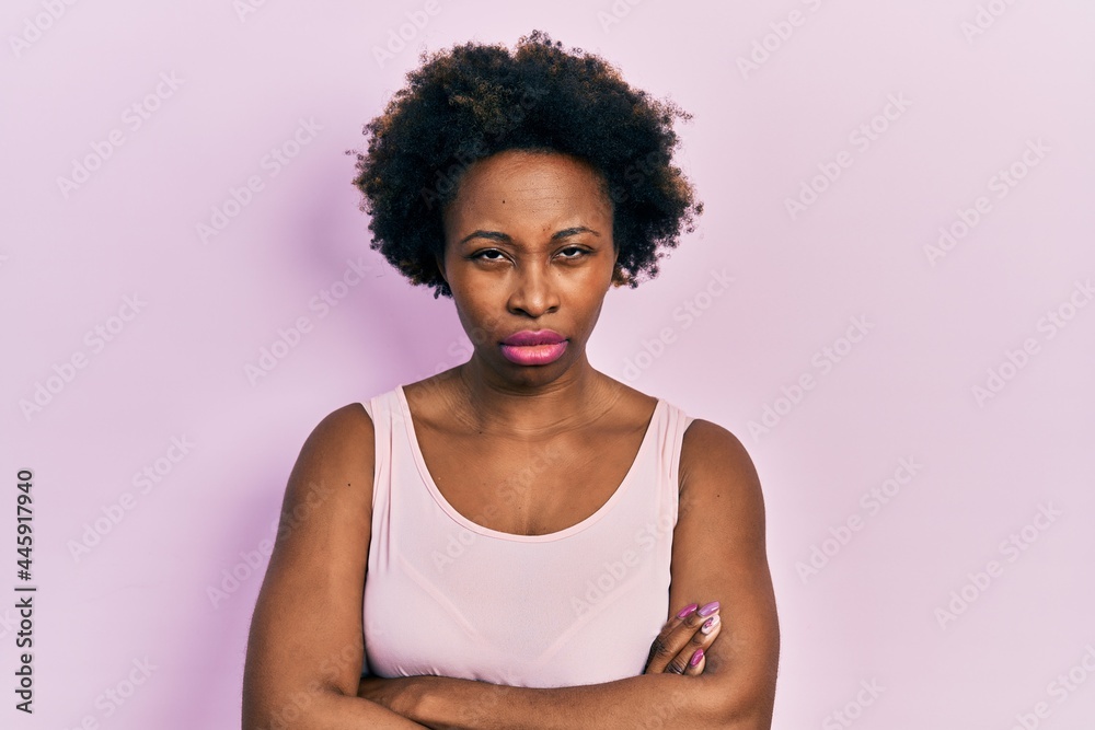 Young african american woman wearing casual sleeveless t shirt skeptic and nervous, disapproving expression on face with crossed arms. negative person. Young african american woman wearing casual sleeveless t shirt skeptic and nervous, disapproving expression on face with crossed arms. negative person.