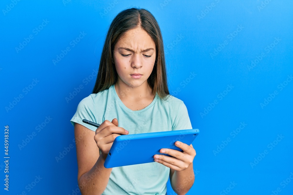 Beautiful brunette little girl using touchpad drawing on screen skeptic and nervous, frowning upset because of problem. negative person. Beautiful brunette little girl using touchpad drawing on screen skeptic and nervous, frowning upset because of problem. negative person.