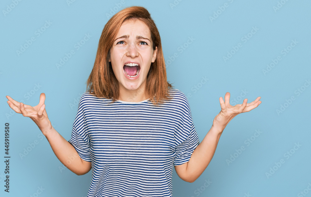 Young caucasian woman wearing casual clothes crazy and mad shouting and yelling with aggressive expression and arms raised. frustration concept. Young caucasian woman wearing casual clothes crazy and mad shouting and yelling with aggressive expression and arms raised. frustration concept.
